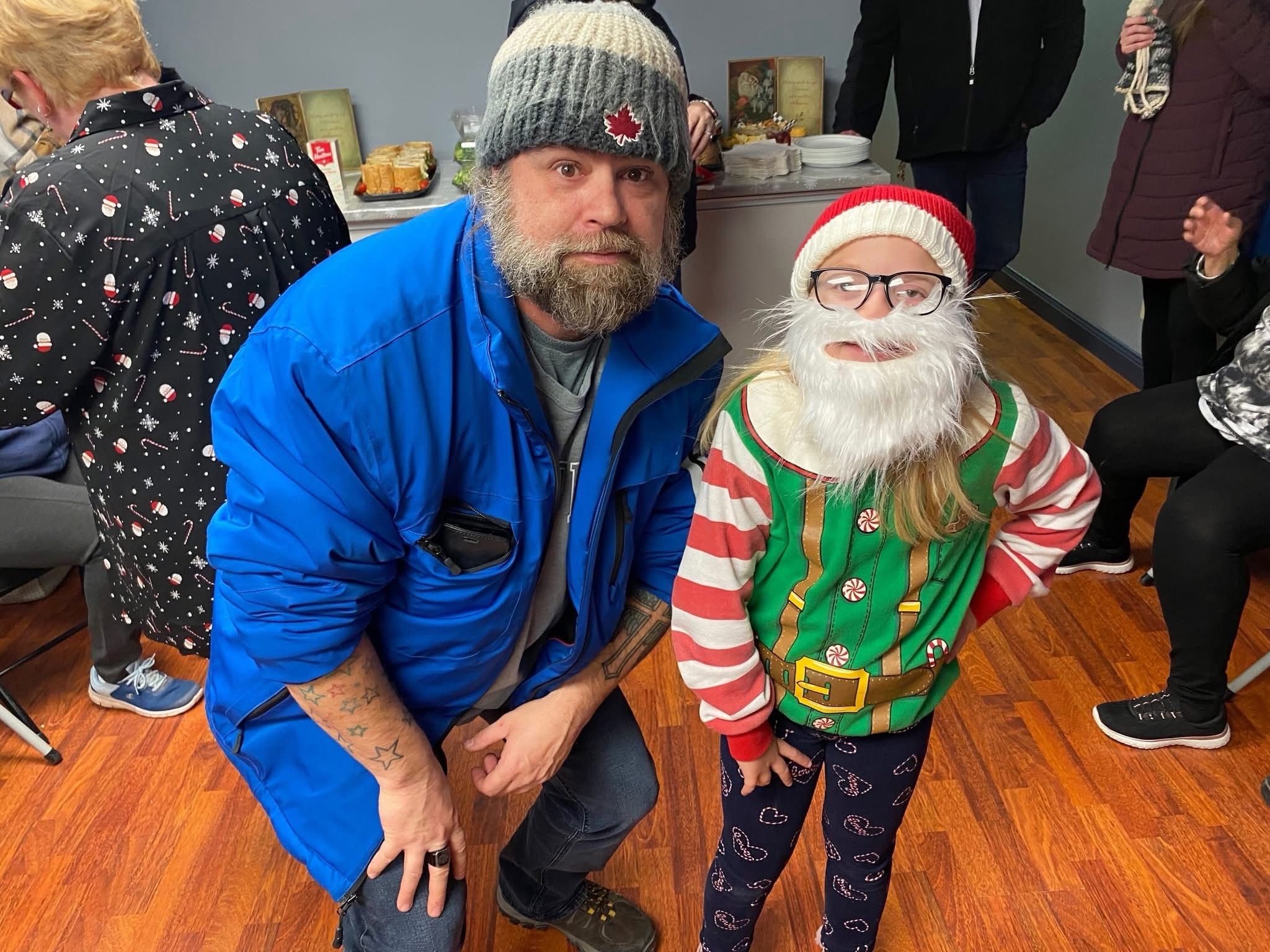 Community members at a holiday gathering, including a child dressed as an elf